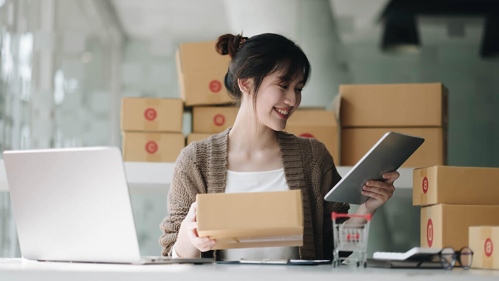 Woman holding a tablet and package.