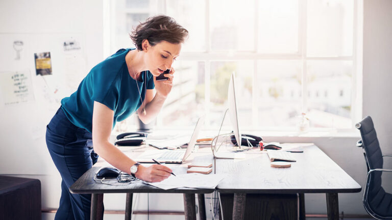 Woman on the phone writing on a table.