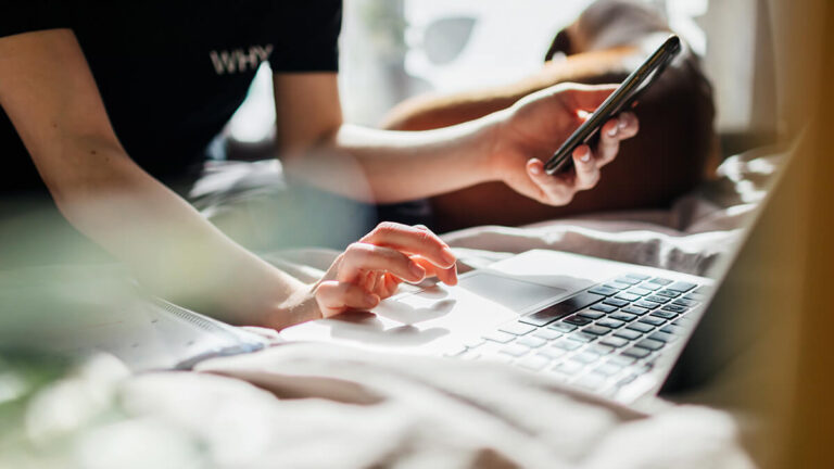 Business owner using cell phone and laptop.