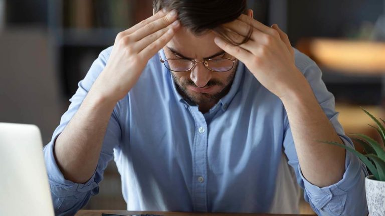 Stressed man with hands on forehead.