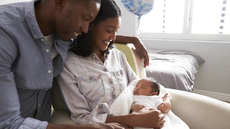 Husband and wife holding newborn in the hospital.