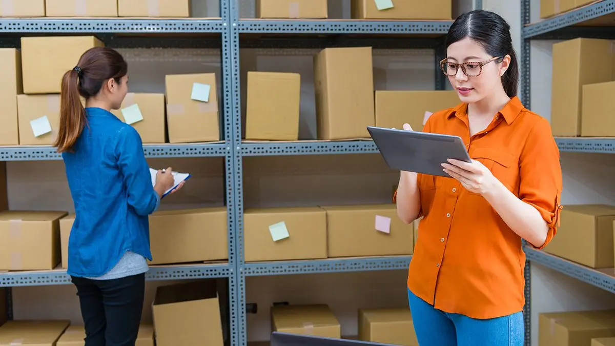 two women in warehouse taking notes for their records