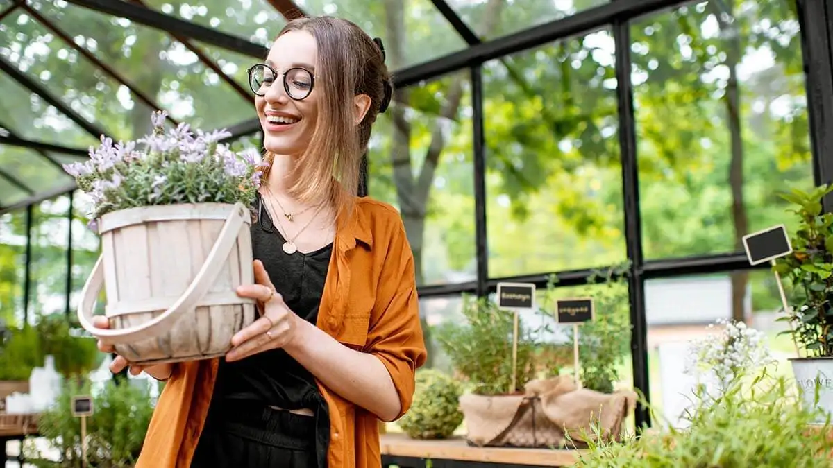 Woman smiling at a plant in her hands.