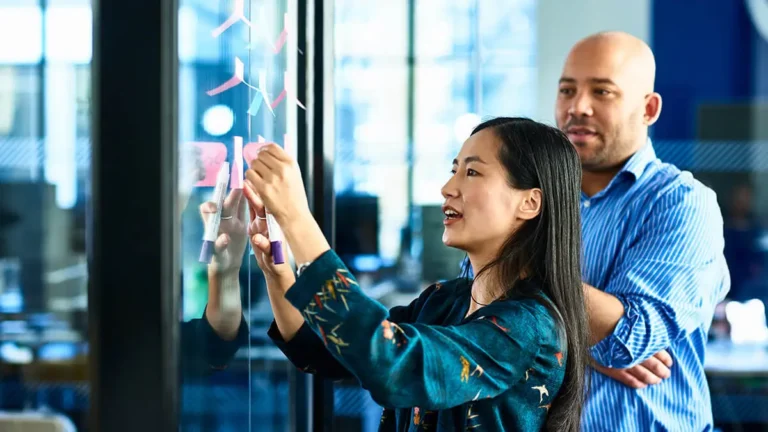 Woman hanging sticky notes on wall.