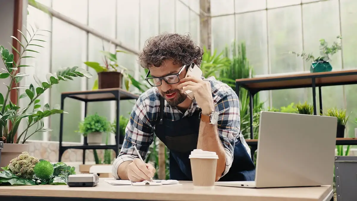 Business owner on the phone, surrounded by plants.