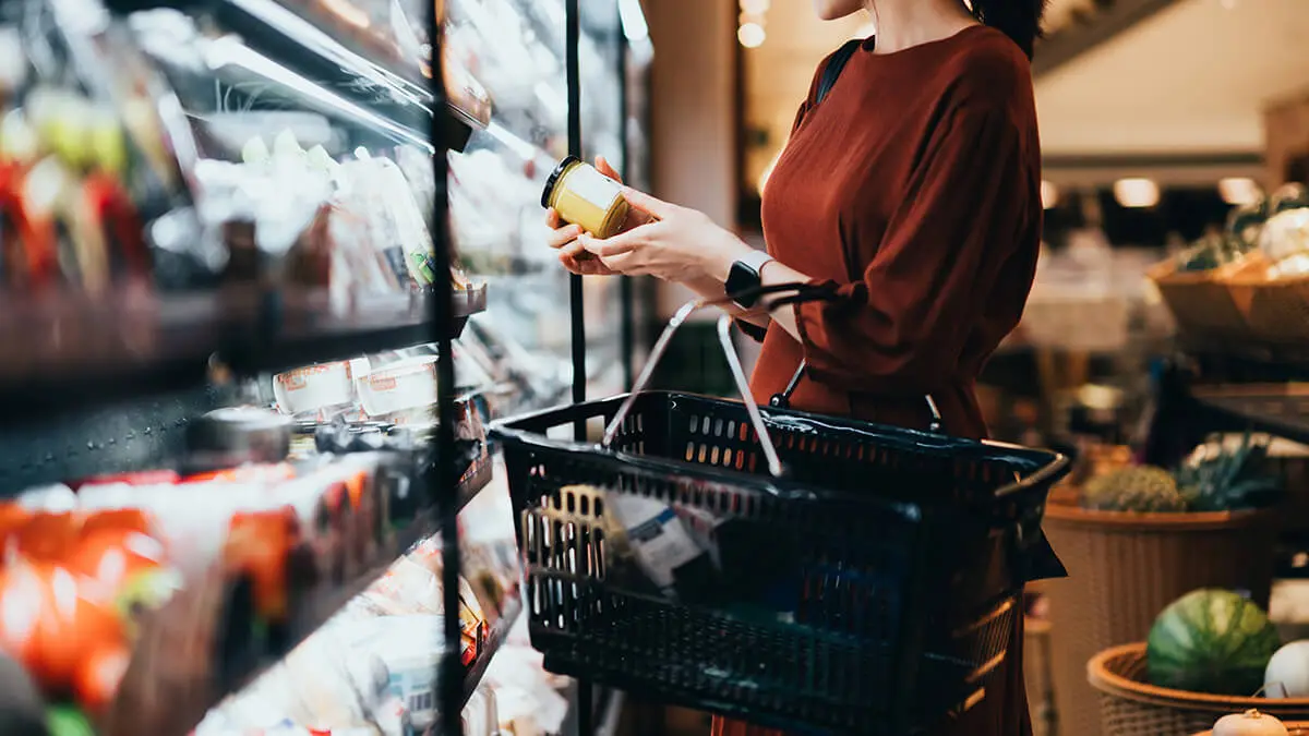 Woman shopping at a grocery store looking for discount pricing.