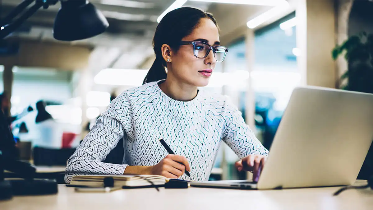 Woman with glasses using a laptop.