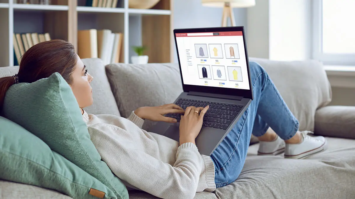 Woman online shopping while on the couch.