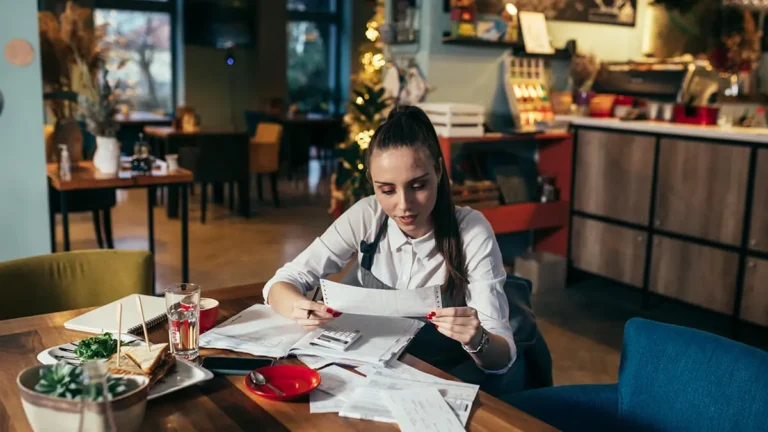 Business owner working at night, holding a check.