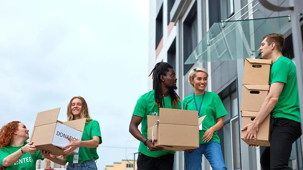 People smiling and carrying donation boxes.