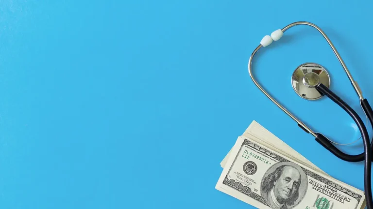 Money and stethoscope on blue background