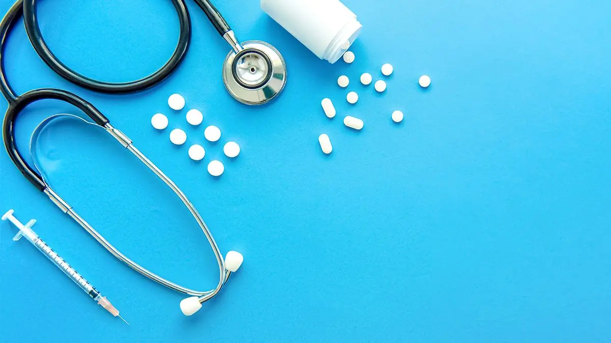 Stethoscope and pharmaceutical pills on a blue background