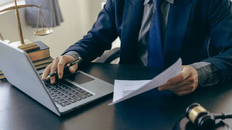 Business tax attorney using the laptop and looking at a document.