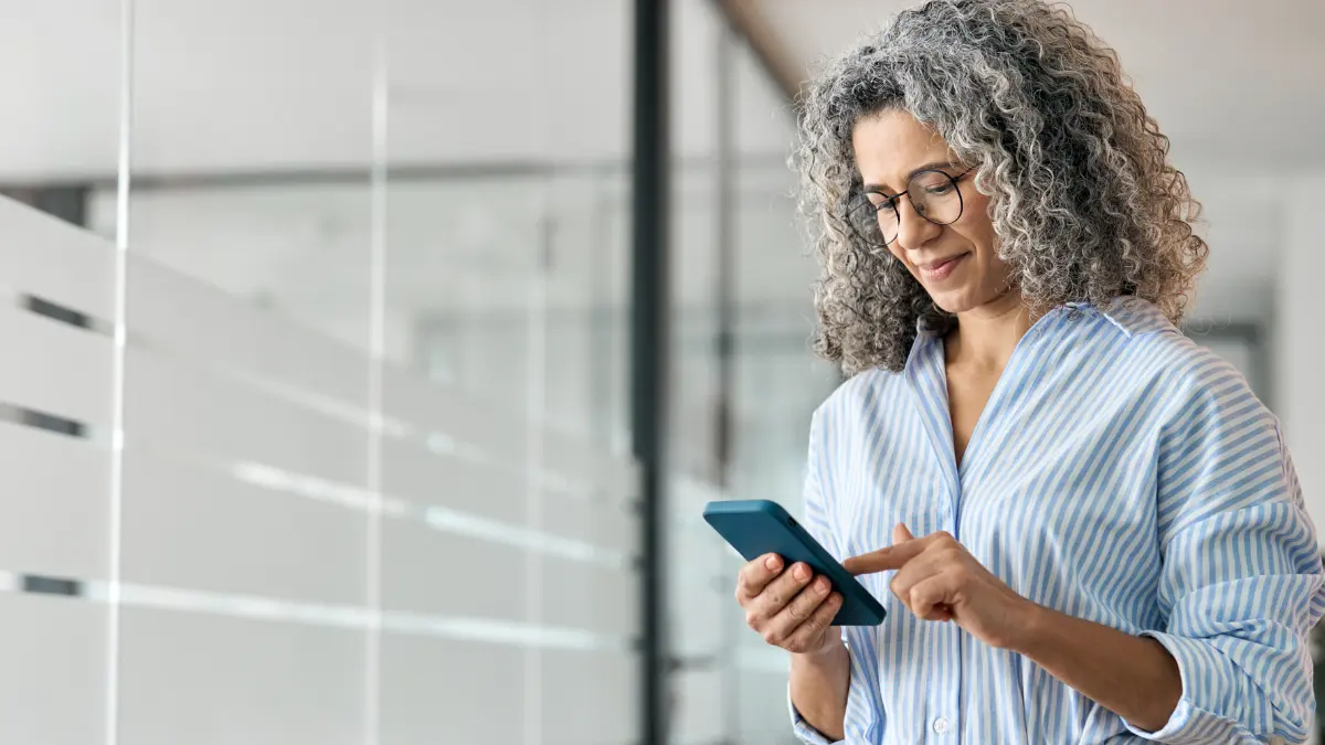 Woman looking at payroll features and benefits on her cell phone.